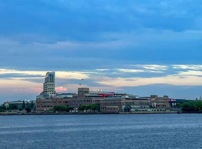 Building across blue water set against blue and pink setting sky.