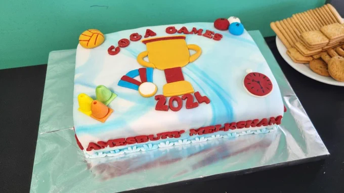 Picture of a rectangular cake decorated with white icing and a picture of a trophy surrounded by the words GOGA games 2024.
