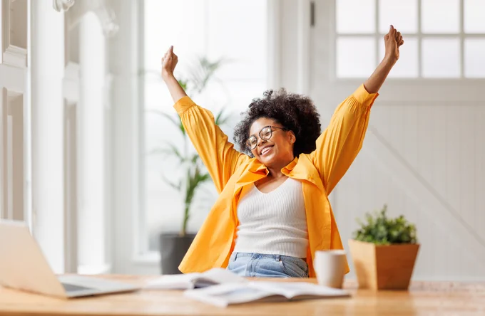 A young woman celebrates while working from home
