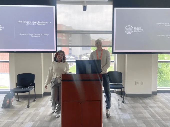 Two people stand behind a podium and smile. 