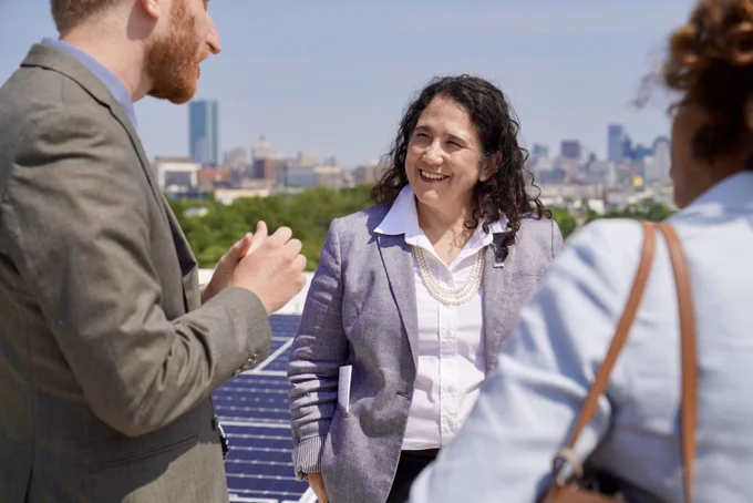 Administrator Guzman and two others in front of solar panels.