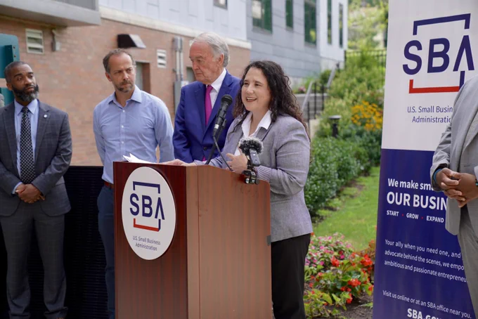 Administrator Guzman speaks at a podium with the SBA logo and signage. Senator Markey and three others are in the background.