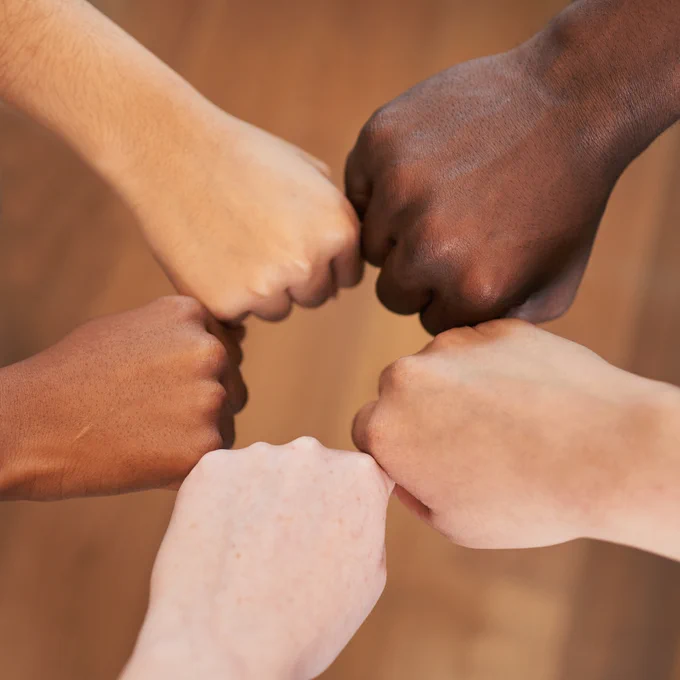 Fists of different skin tones in a circle.