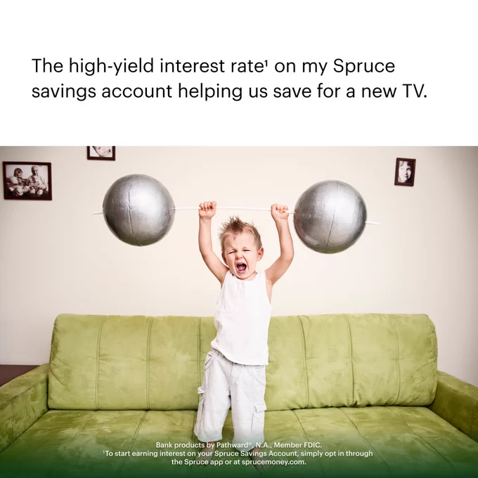 A meme-style image depicts a toddler standing on a green couch, making an expression of exertion as he lifts a comically oversized set of barbell weights over his head. Black text reads “The high-yield interest rate1 on my Spruce savings account helping us save for a new TV. Bank products by Pathward®, N.A., Member FDIC. 1To start earning interest on your Spruce Savings Account, simply opt in through the Spruce app or at sprucemoney.com.”