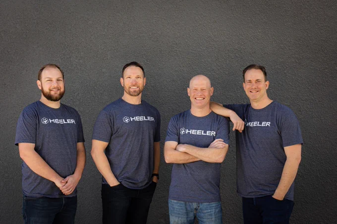 Four men in matching t-shirts pose for a picture.