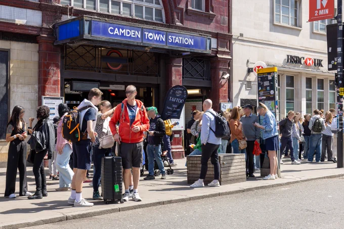 People stand on the pavement outside Camden Town Station.