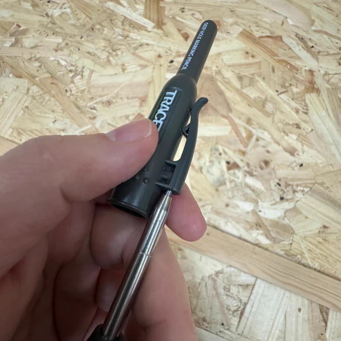 A hand holding the sharpener lid against a plywood background.