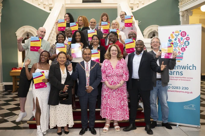 A group of smiling people holding certificates in their hands in Woolwich Town Hall
