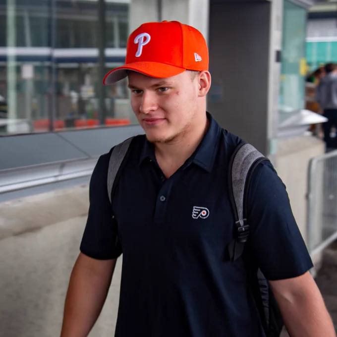 Matvei Michkov in an orange Phillies hat and black Philadelphia Flyers shirt.