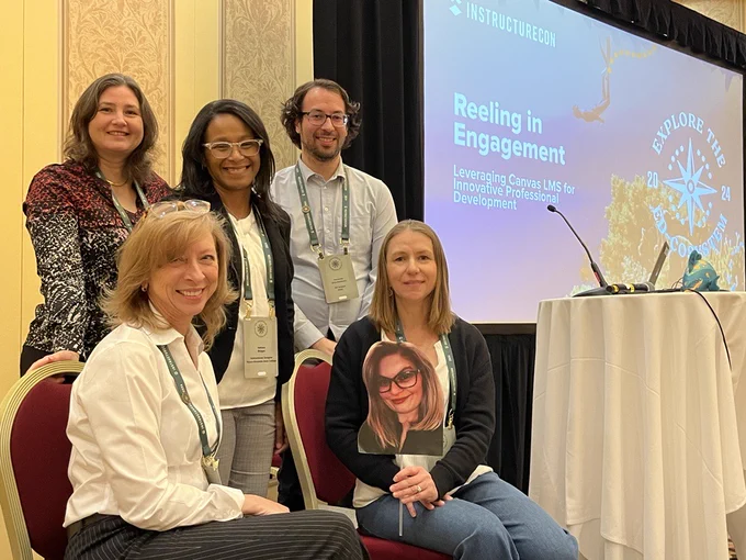 A group of people smiling at the camera standing in front of a presentation screen. 