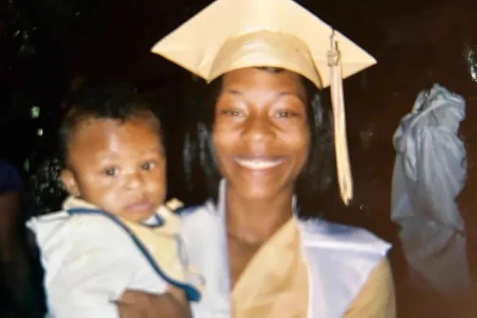 A photo of Sonya Massey wearing a graduation cap, holding a baby, and smiling at the camera