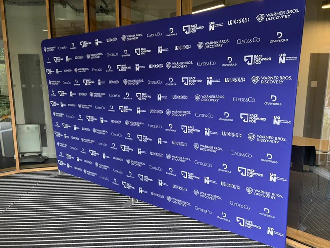 Image shows a Step and Repeat banner with the following companies logos on it: the University of Northampton, Warner Bros Discovery, Clyde and Co, Diversitile and Race Forward Pod.