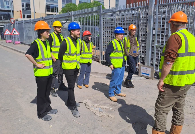Group of students in hard hats and hi-viz tabards in Bradford city centre.