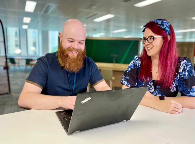 Two colleagues working together on a laptop in a DWP Digital hub.