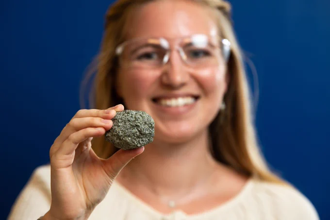 Photo of intern Madeline Bartels smiling at the camer, while holding a rock