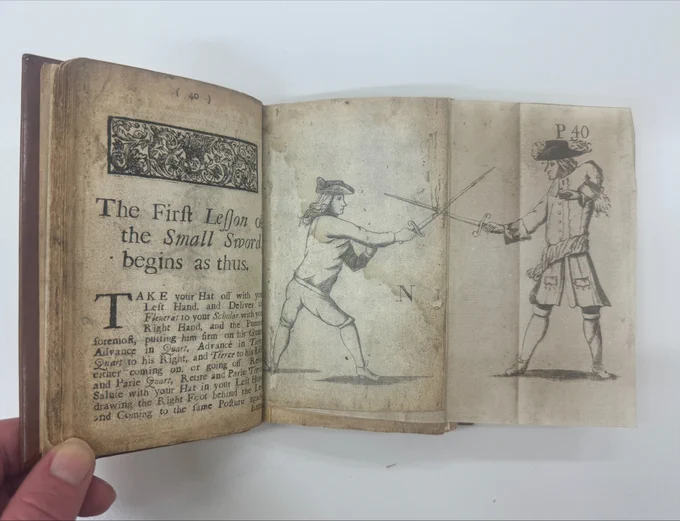 photo of book with fold out illustration of two men sword fighting