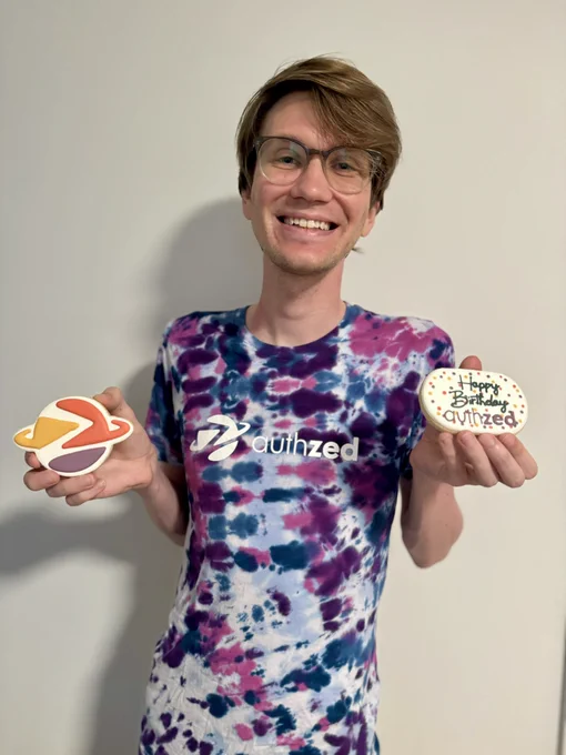Myself holding two cookies: one shaped like the authzed logo and the other that says "Happy Birthday authzed"