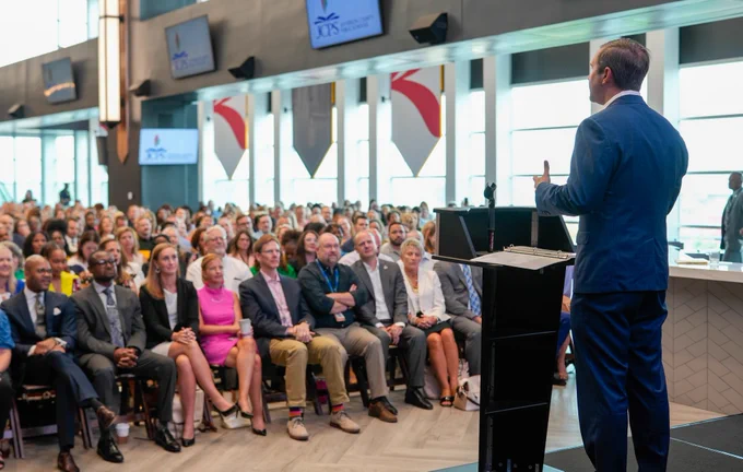 An image of Governor Beshear speaking to a seated crowd in Louisville.
