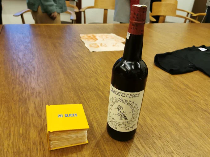 The '20 Slices' book made of American cheese slices, next to a bottle of Laureate's Choice Oloroso Seco Sherry on a wooden table.