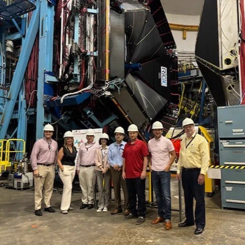 group photo of people in hard hats in front of large equipment