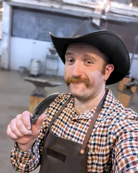 Joe poses while holding up the knife he made