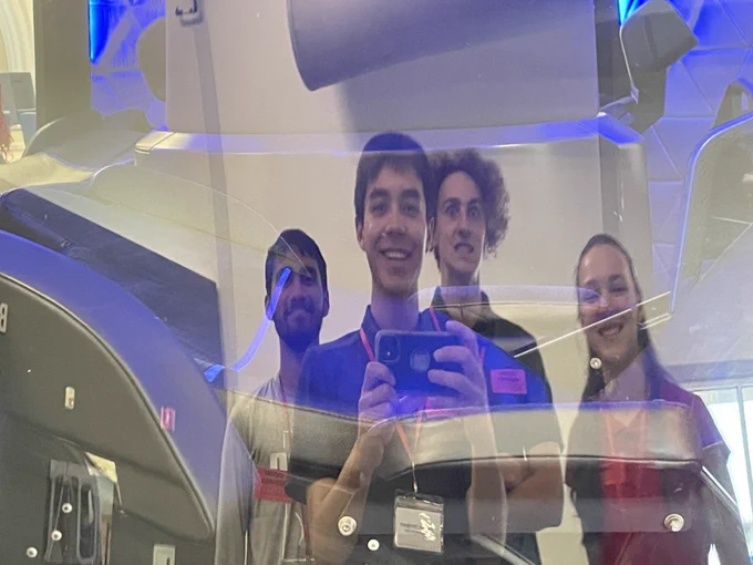 four people taking a picture of their reflections on a window