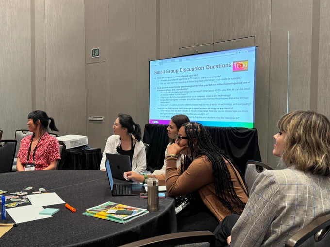 Members of UCLA's computer science equity team and Girls Who Code host and attend a workshop at CSTA 2024. Individuals in the photo are looking at a speaker off-screen. 