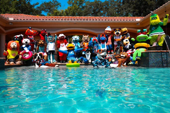 A photo of several NHL mascots posing together for a group photo by a pool in summer outfits.