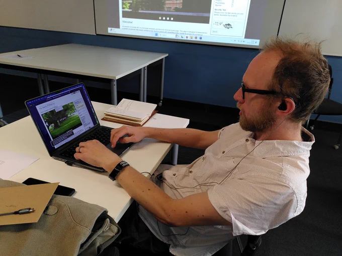 Ian using a laptop with headphones, concentrating hard.