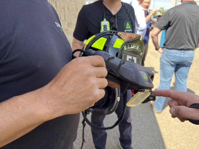 A close-up view of a person demonstrating a C-THRU Helmet to others outdoors.