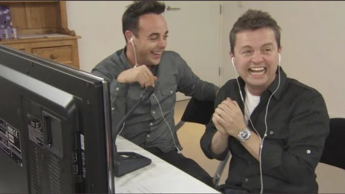 Ant and Dec sitting at a monitor, with earpieces in.