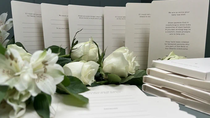 Some of the baby loss resources displayed with white lilies and roses