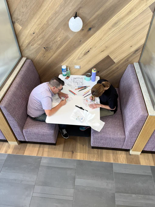 Two people sitting at a booth coloring