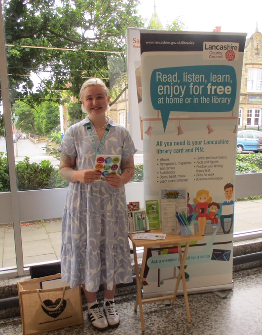 member of staff with library display in supermarket