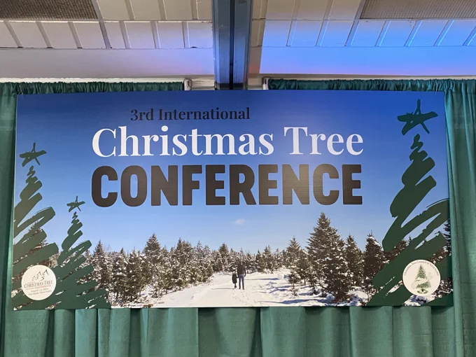 Banner on a wall. The banner says Third International Christmas Tree Conference. 