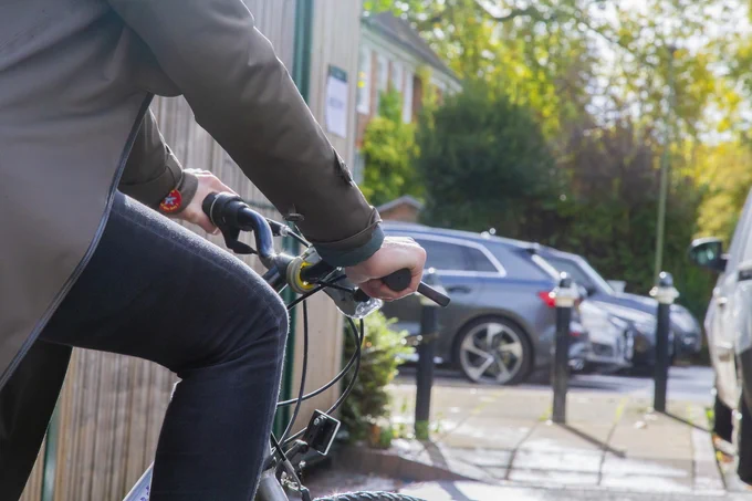 right side of a cyclist in the foreground, on a residential street with parked cars