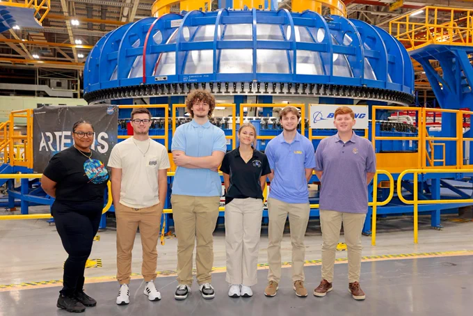A group of NASA Michoud interns poses for a photo in front of SLS rocket hardware at NASA's Michoud Assembly Facility.