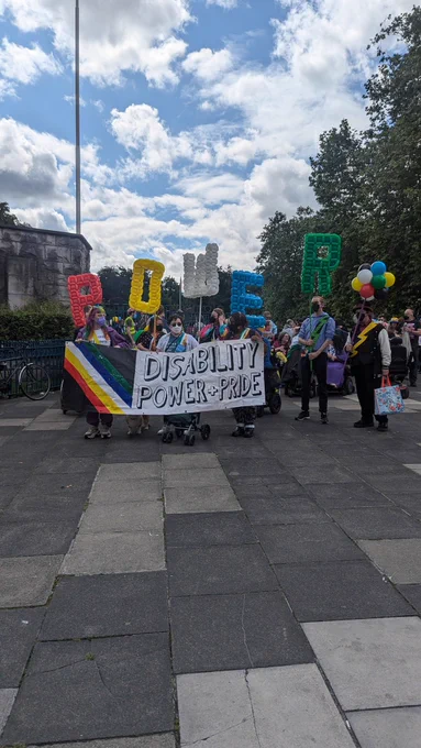 The front of the crowd with a banner saying Disability Power and Pride. There are people holding balloons which spell out POWER. 