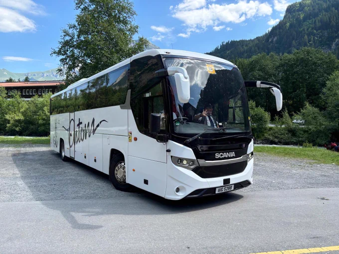 Coach leaving car park with mountain behind