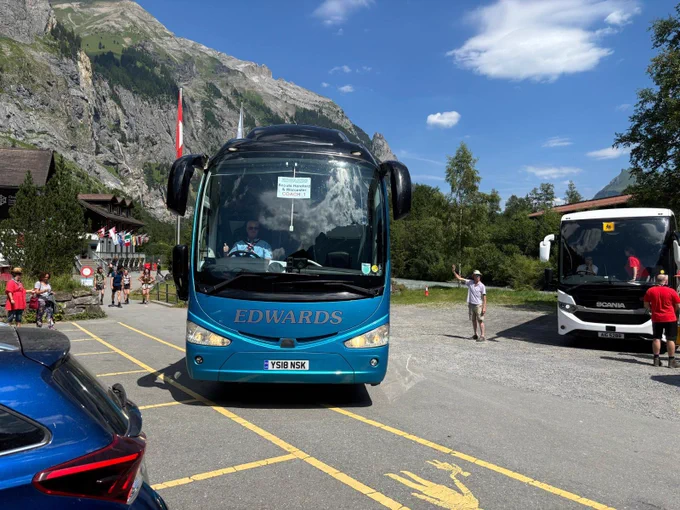 Coach leaving car park with mountain behind
