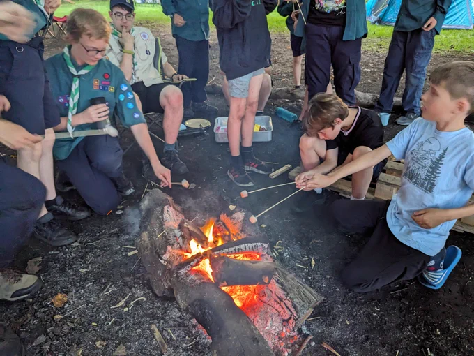 Scouts toasting marshmallows on a small fire