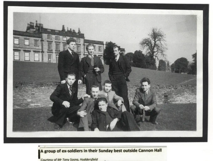 A black and white photo shows seven men, dressed in formal attire, posing together on the grounds outside Cannon Hall. Five men stand, while two kneel in the foreground. Cannon Hall is visible in the background, with trees and a stone wall in the scene.