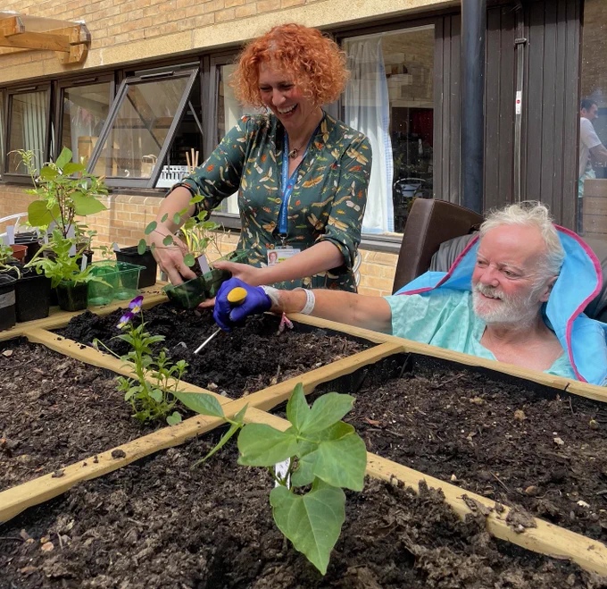 Two people gardening and smiling.