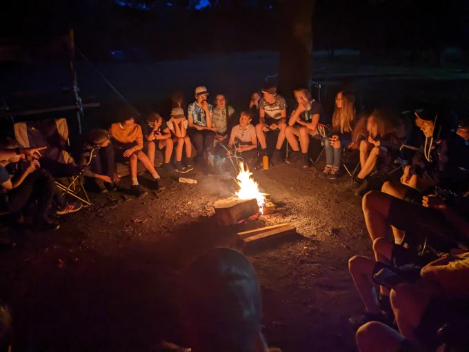 Scouts sat around a campfire in the dark 