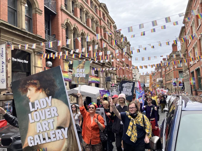 People marching at Pride with a 'Lady Lover Art Gallery' placard