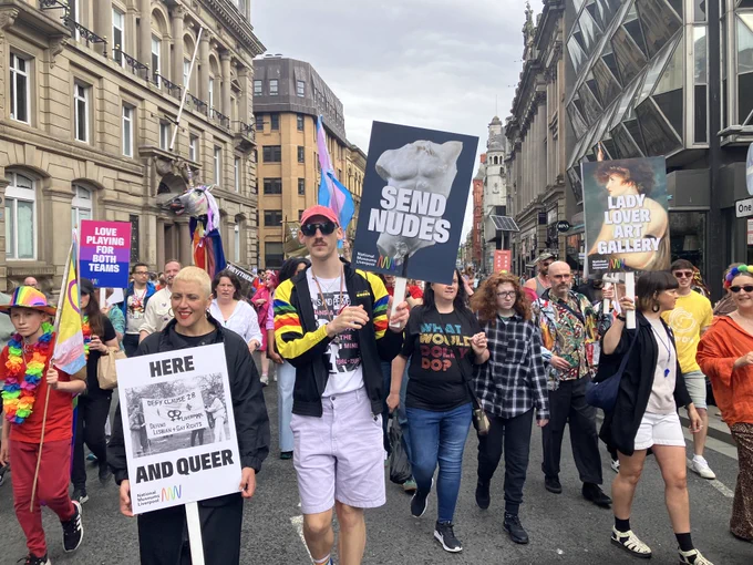 People marching in Pride with 'Send nudes' and 'Here and Queer' placards