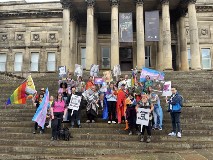 The Pride march group, on the steps of the museum, holding flags