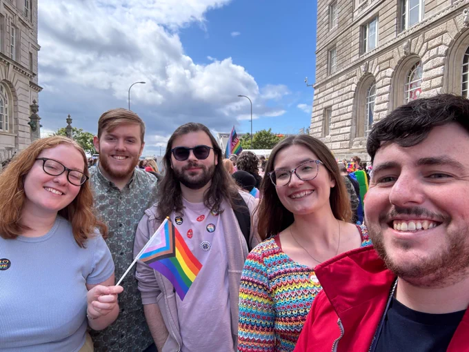 Jamescape staff and friends smiling together in a selfie by the Liverpool Waterfront.