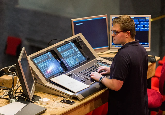 A student working at a lighting desk in the theatre
