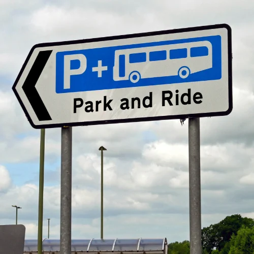 A street sign pointing to park and ride with a white P   graphic of a bus on a blue background